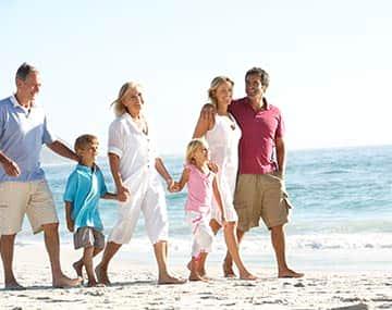 Parents and grandparents on super visa are walking on beach with children